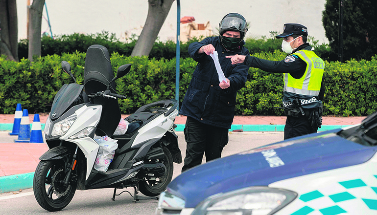 Ein Polizist kontrolliert einen Verkehrsteilnehmer während der Ausgangssperre. Foto: EFE