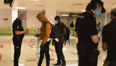 Zwei Migranten werden vor Abflug am Südflughafen von der Nationalpolizei kontrolliert. Foto: EFE